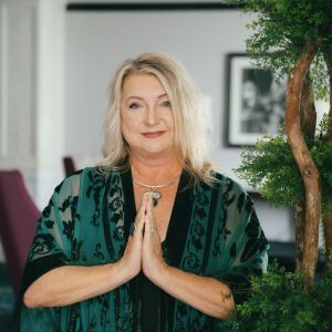 Woman with hands in Namaste gesture indoors.